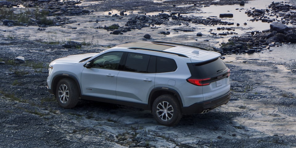 Birds-eye View of a White GMC Acadia Mid-Size SUV Parked on a Beach at Sunset