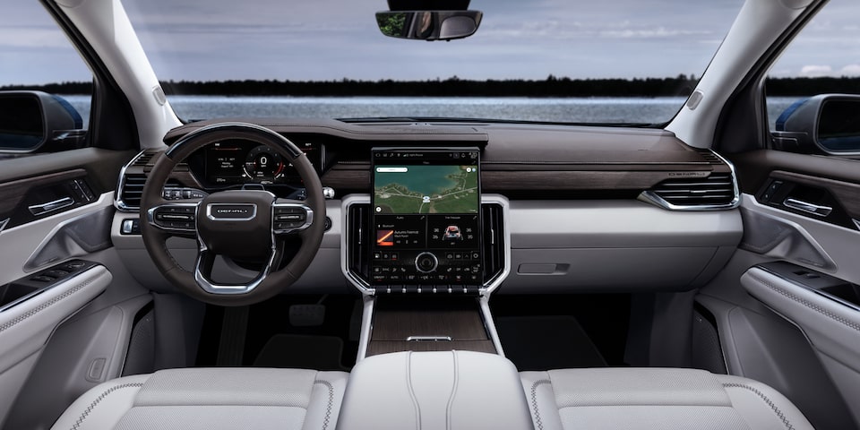 View of the GMC Acadia's White Interior and View of the Steering Wheel and Infotainment System