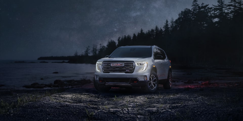 The 2025 GMC Acadia Parked on a Beach at Night with the Headlights on