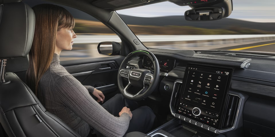A Woman Sitting in the Drivers Seat of the GMC Acadia AT4 SUV Using Super Cruise Hands-Free Driving Technology