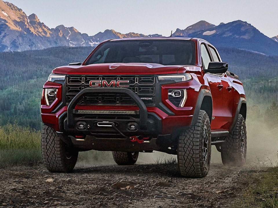 A Red 2025 GMC Canyon AT4 Off-roading on a Rocky Trail Kicking Up Dirt