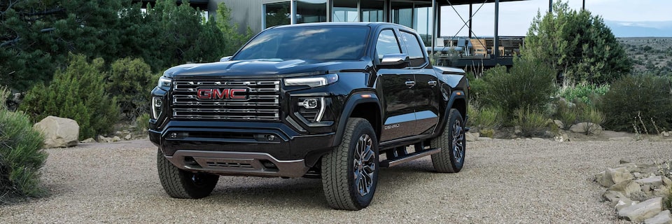 Three-quarter View of a 2025 GMC Canyon Denali Parked Outside of a Modern Mountain Cabin
