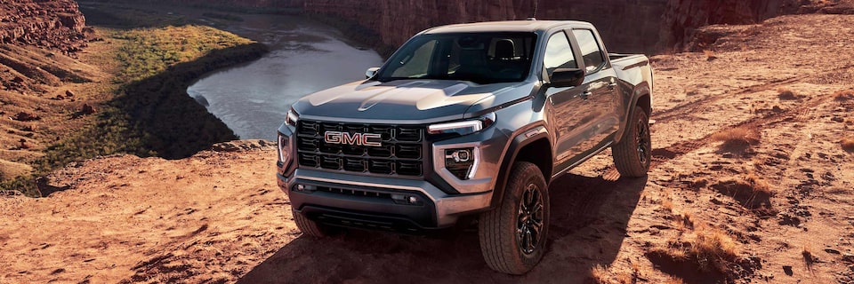 Two 2025 GMC Canyon Trucks Parked in the Desert with Snow Melting in the Background