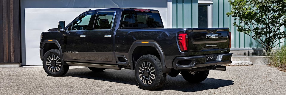 Wide Rear Three-Quarters View of a 2025 GMC Sierra HD Denali Truck Parked on Gravel