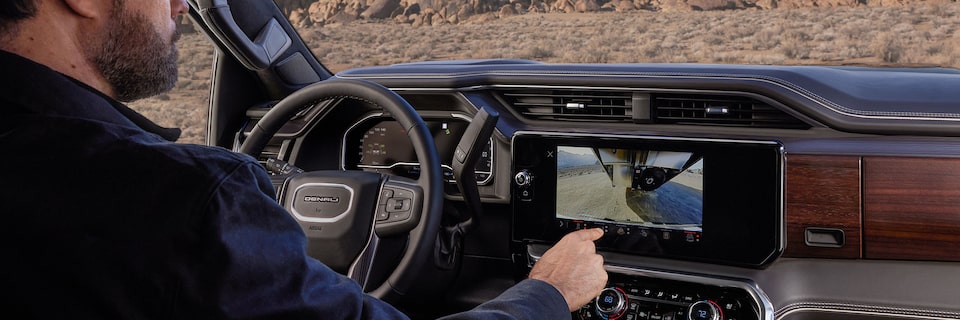 Wide View of a Driver Switching the Camera Views on the Infotainment Screen in a GMC Truck
