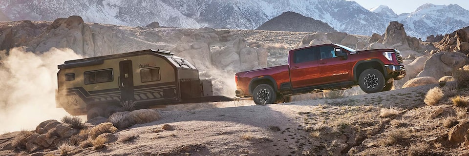 Wide Side View of a 2025 GMC Sierra HD Hauling a Trailer Through the Mountains