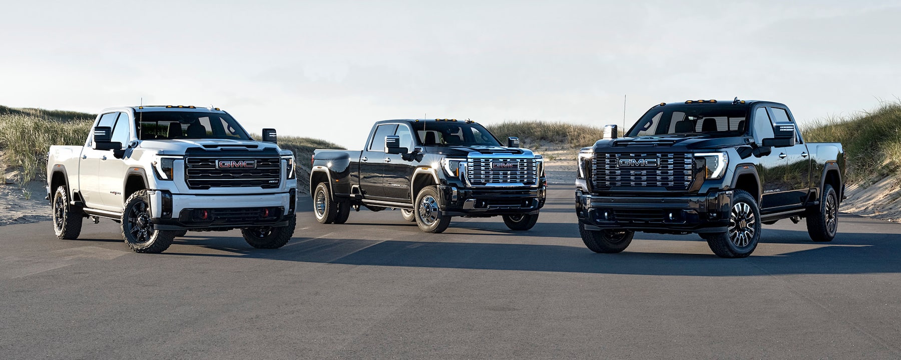 White 2500 Heavy Duty; Black Duramax Turbo-Diesel V8 and Black 3500 Denali Ultimate GMC Sierra's parked side by side.