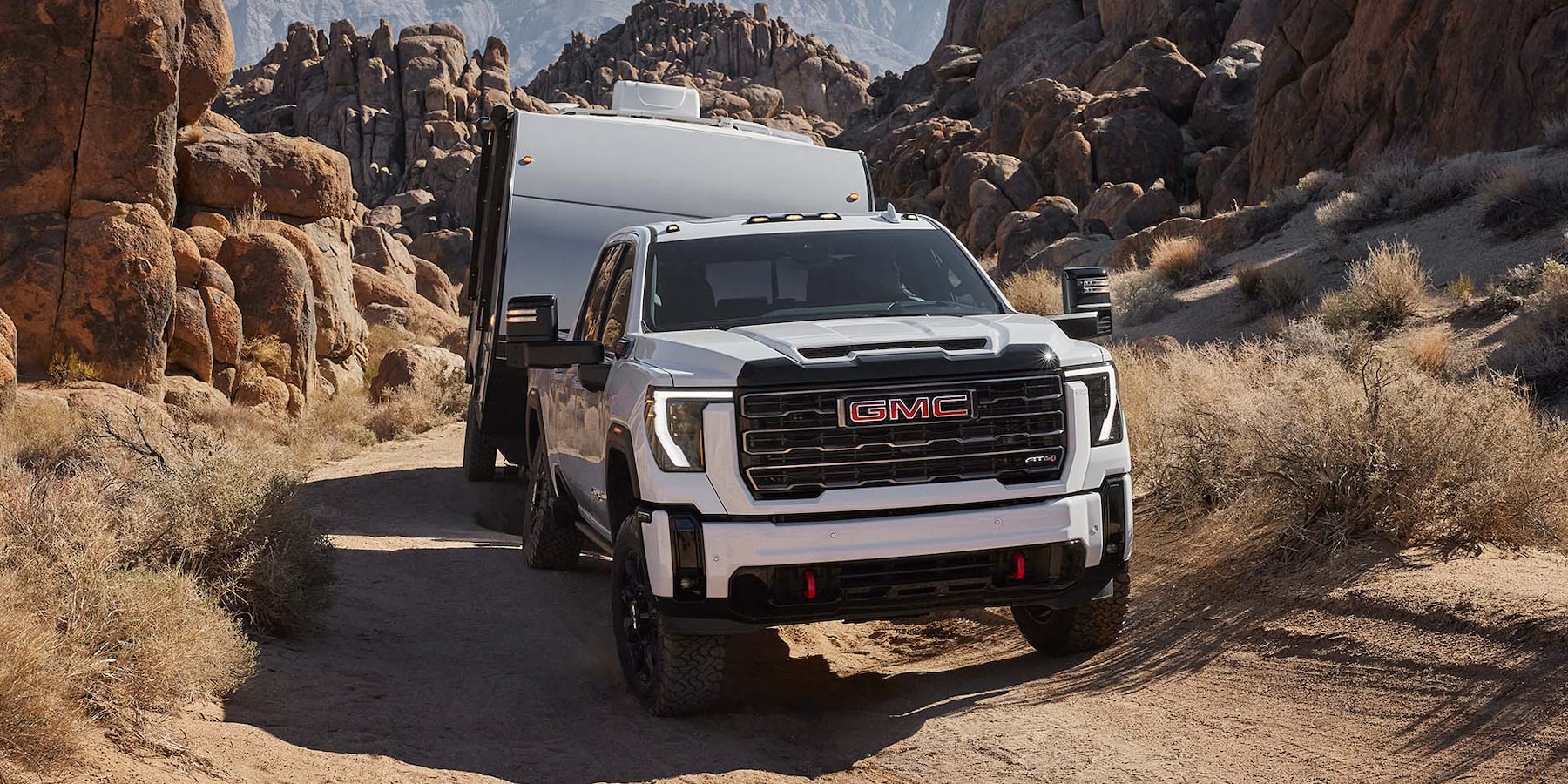 2025 gmc sierra hd in white towing trailer through canyon