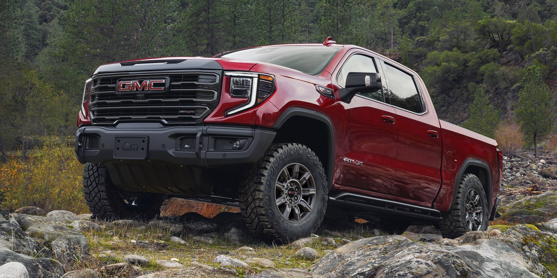 Red 2025 GMC Sierra 1500 AT4X driving over rocks
