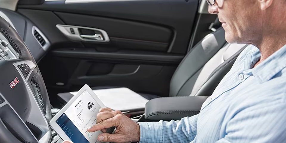 A Person Sitting Inside of a Vehicle Using the Vehicle Insights App on a Tablet