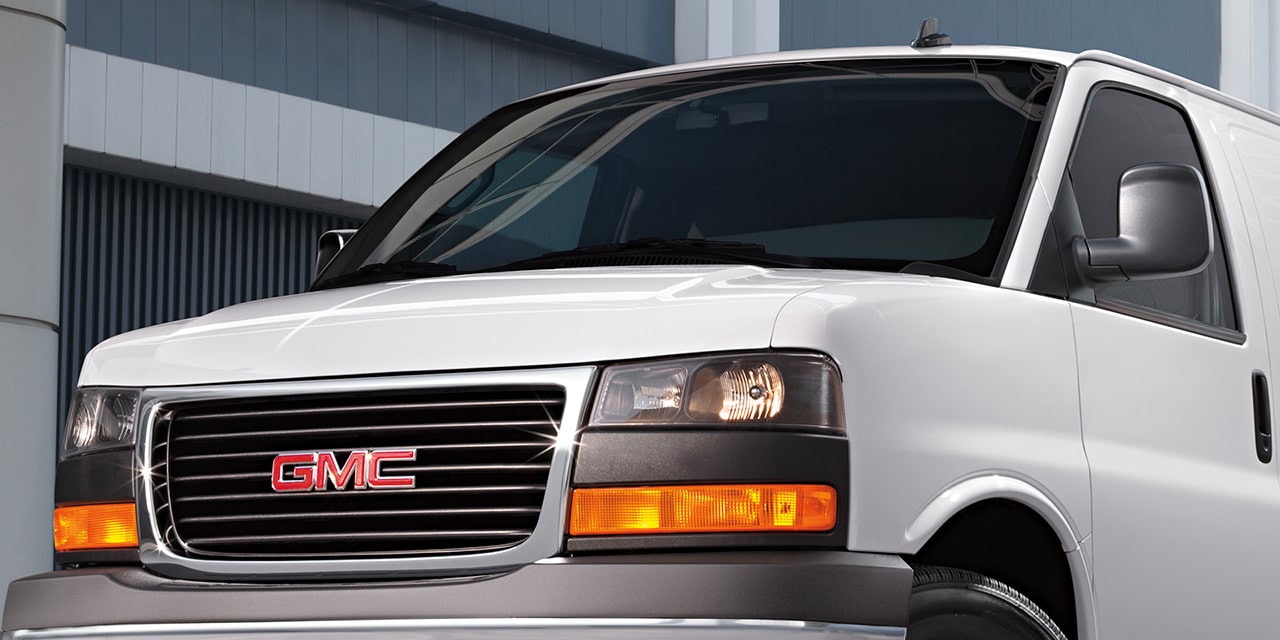 Close-Up Front View of a White 2026 GMC Savana Van, Focusing on the Grille and GMC Logo