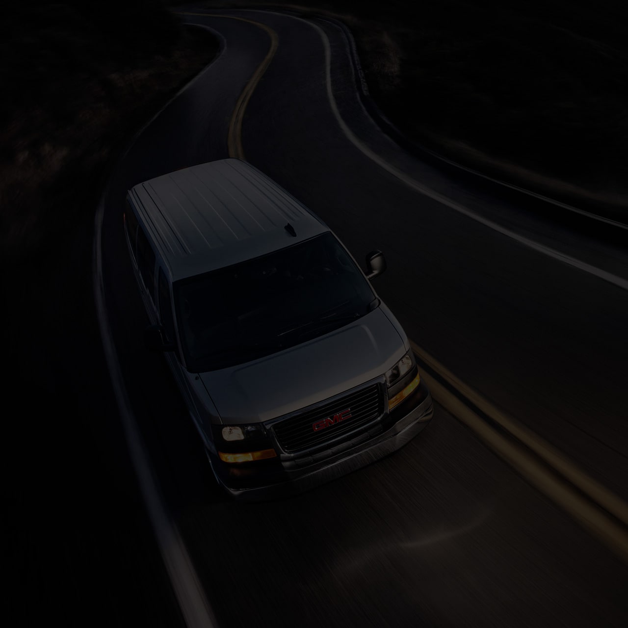 Birds-eye View of a 2026 GMC Savana Passenger Van Driving on an Empty Road at Night