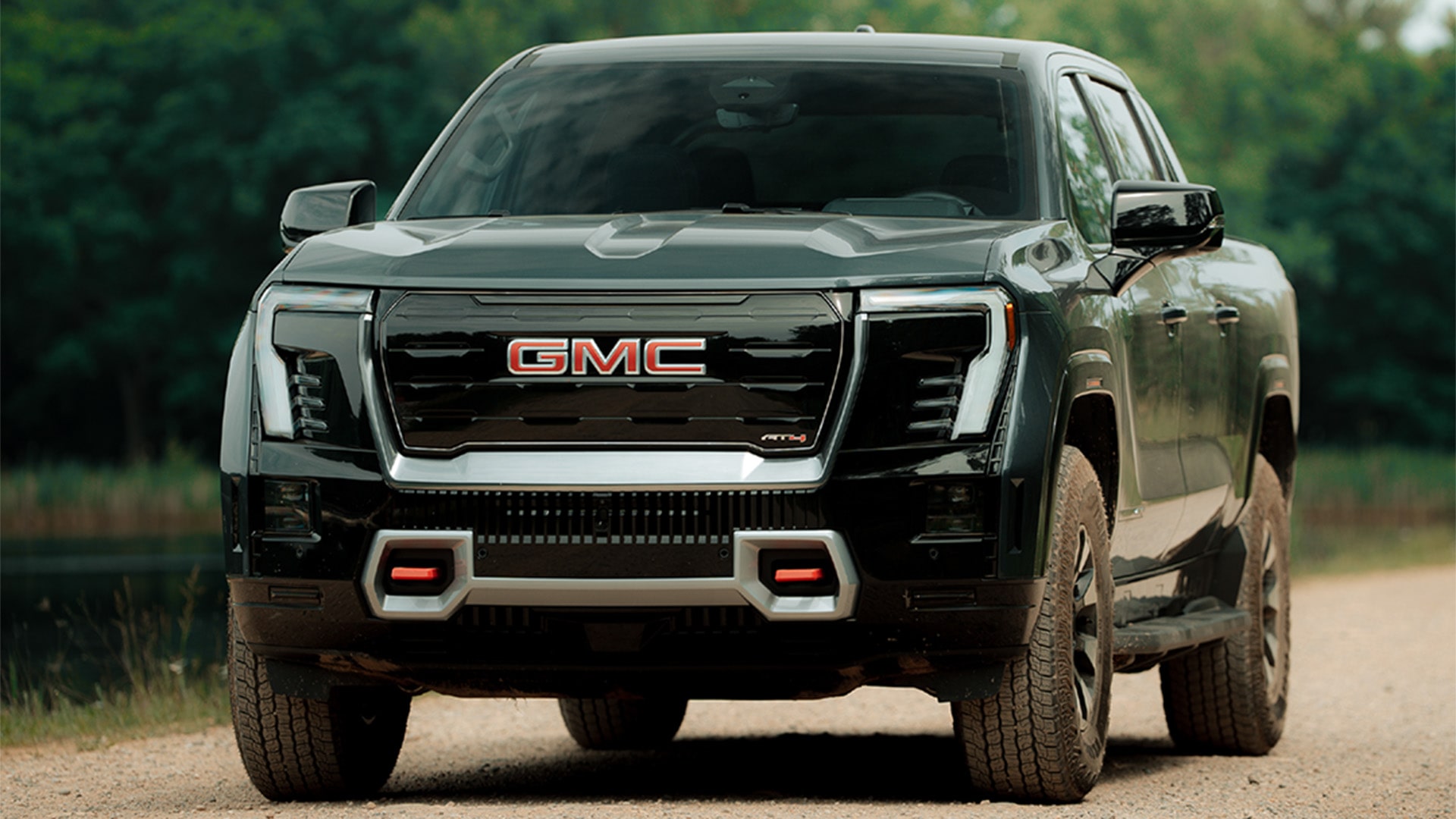 The 2026 GMC Sierra EV AT4 Pickup Truck Pulling a Boat Along a Road on the Coast