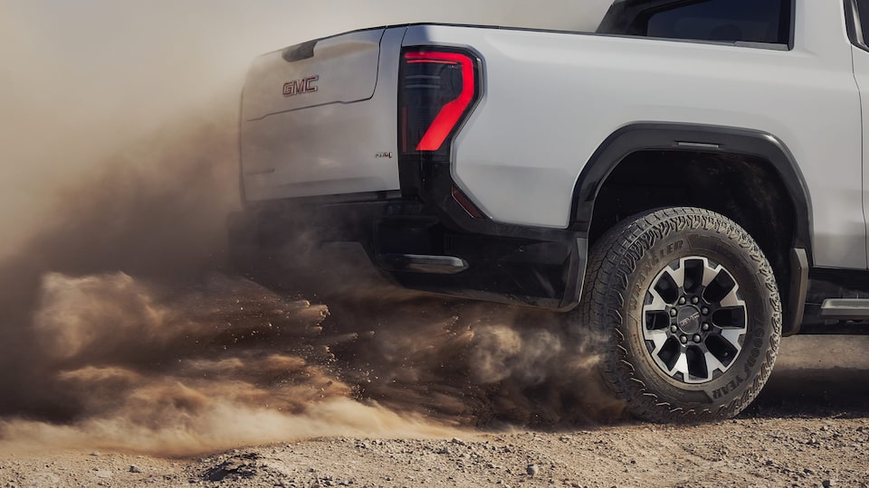 Close-up of the 2026 GMC Sierra EV Pickup Truck's Rear End and Tires Flinging Up Dirt