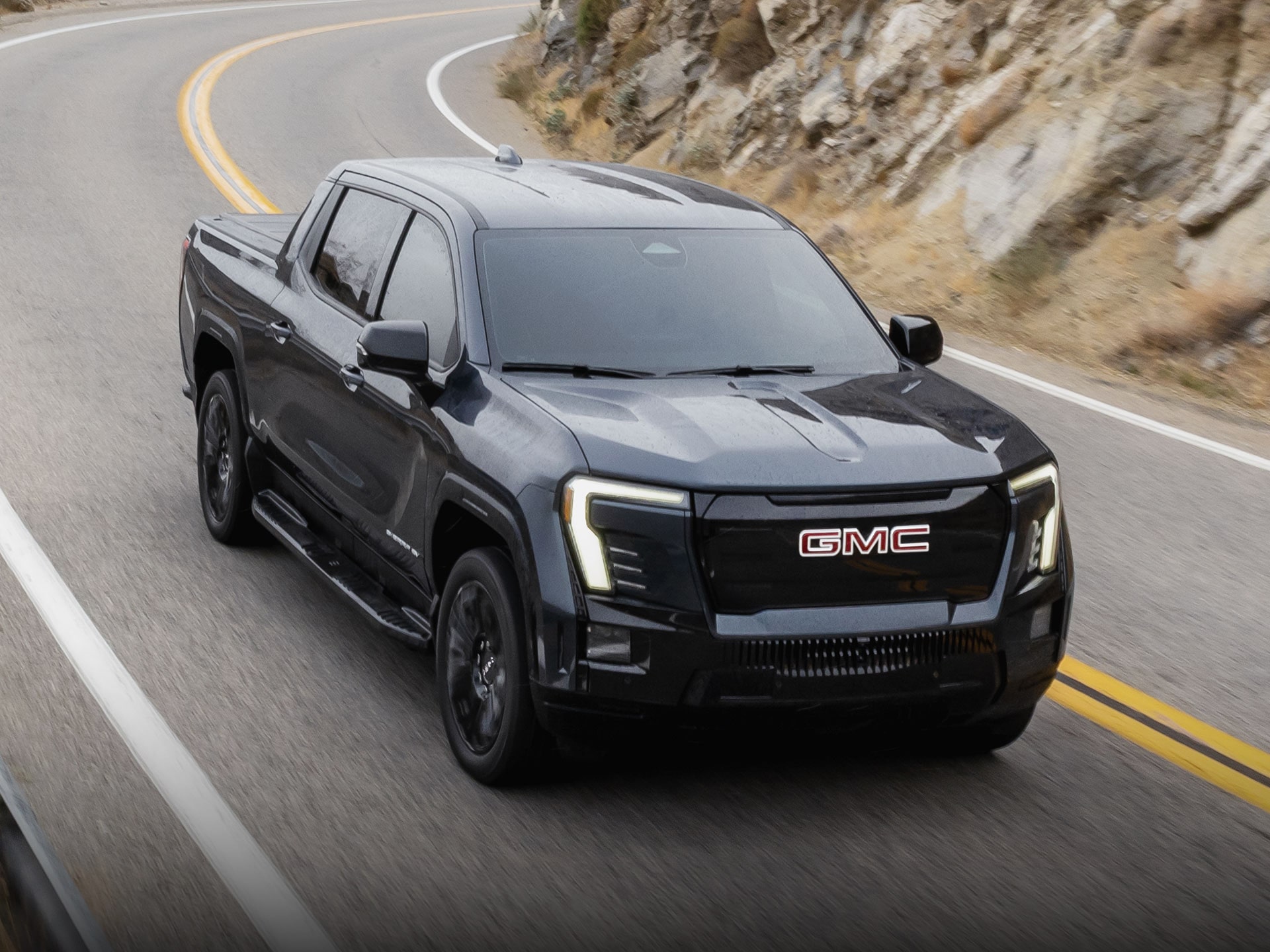 The 2026 GMC Sierra EV Elevation Driving Down a Winding Road