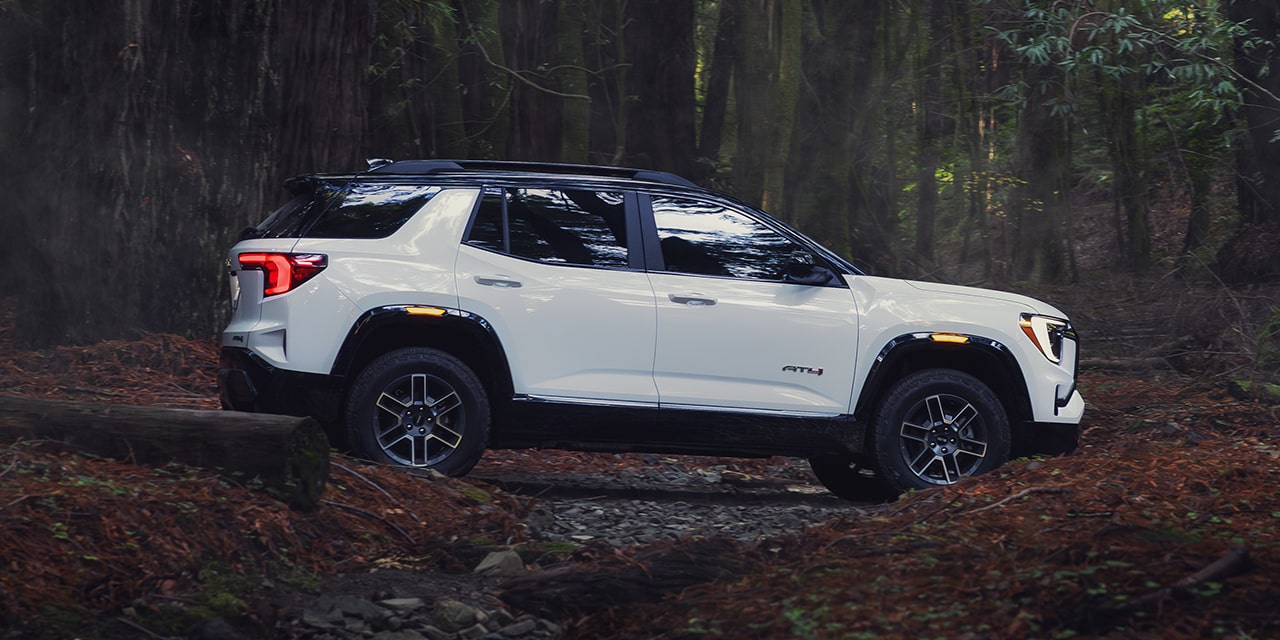 Profile View of the 2026 GMC Terrain AT4 Small Off-Road SUV Driving Through the Forest