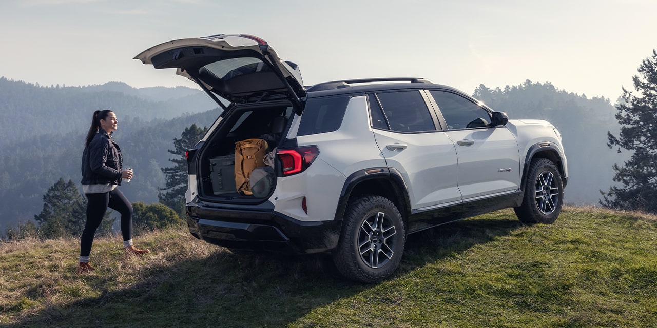 Rear View of the Open Tailgate on the 2026 GMC Terrain AT4 Small Off-Road SUV While A Person Unloads the Cargo