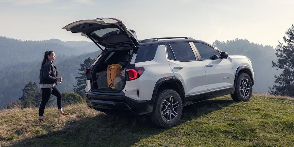 Rear View of the Open Tailgate on the 2026 GMC Terrain AT4 Small Off-Road SUV While A Person Unloads the Cargo
