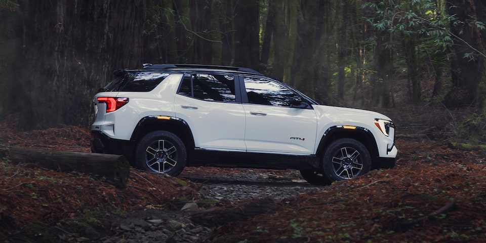 Profile View of the 2026 GMC Terrain AT4 Small Off-Road SUV Driving Through the Woods