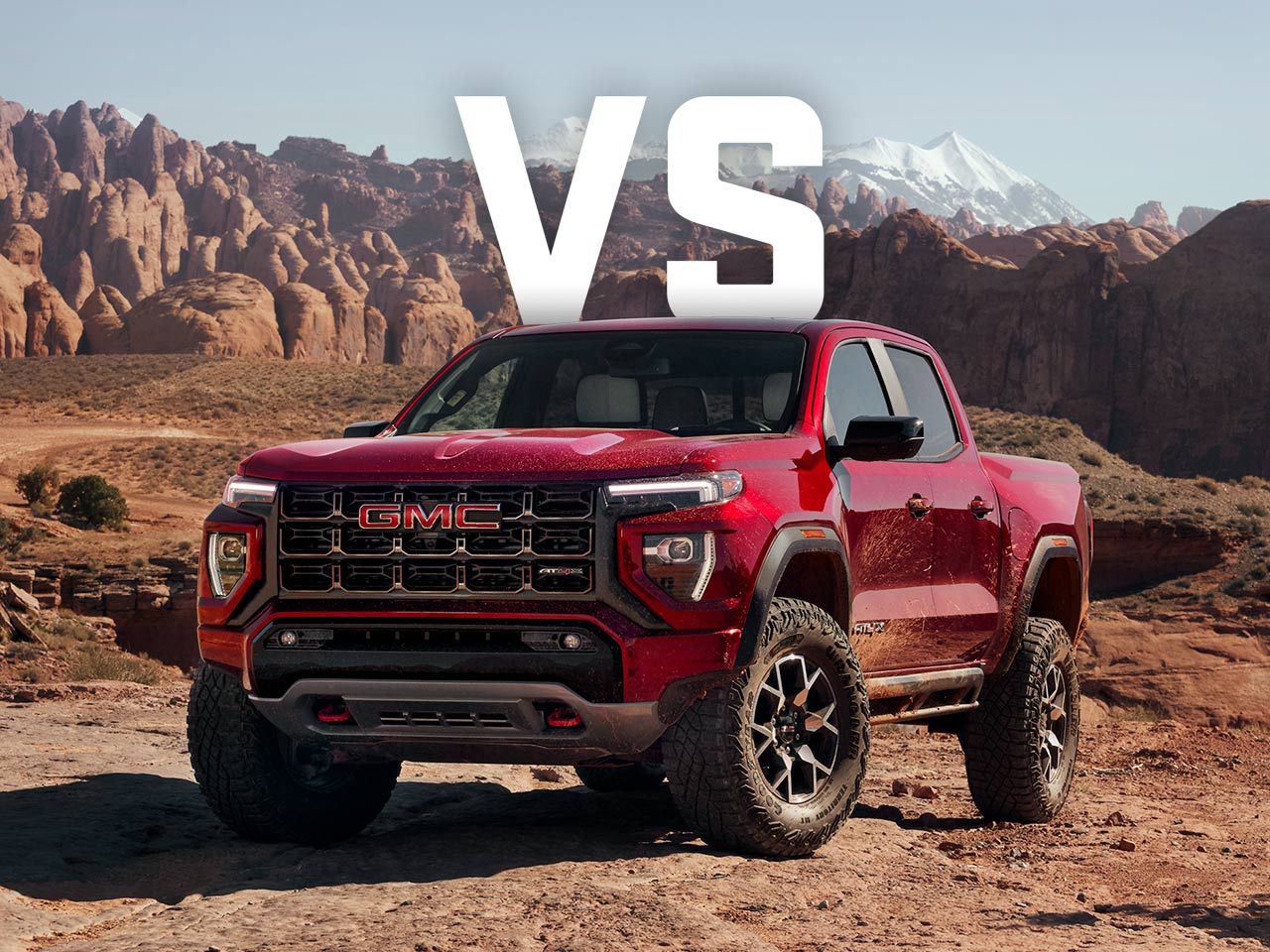 A Red GMC Canyon AT4X Truck on Rocky Desert Terrain with Rock Formations and Mountains and Large White VS Text