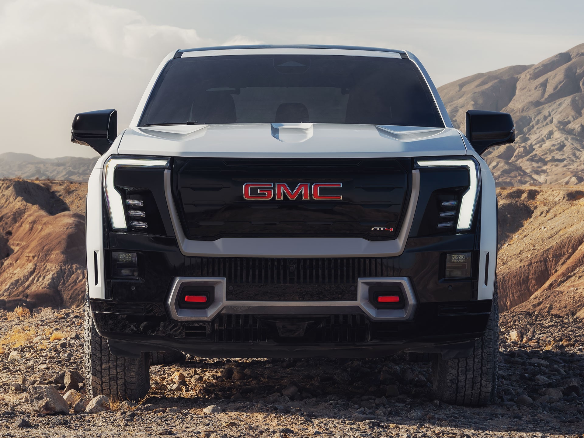 The Front Grille of a White GMC Sierra EV Featuring Iconic Red Recovery Hooks