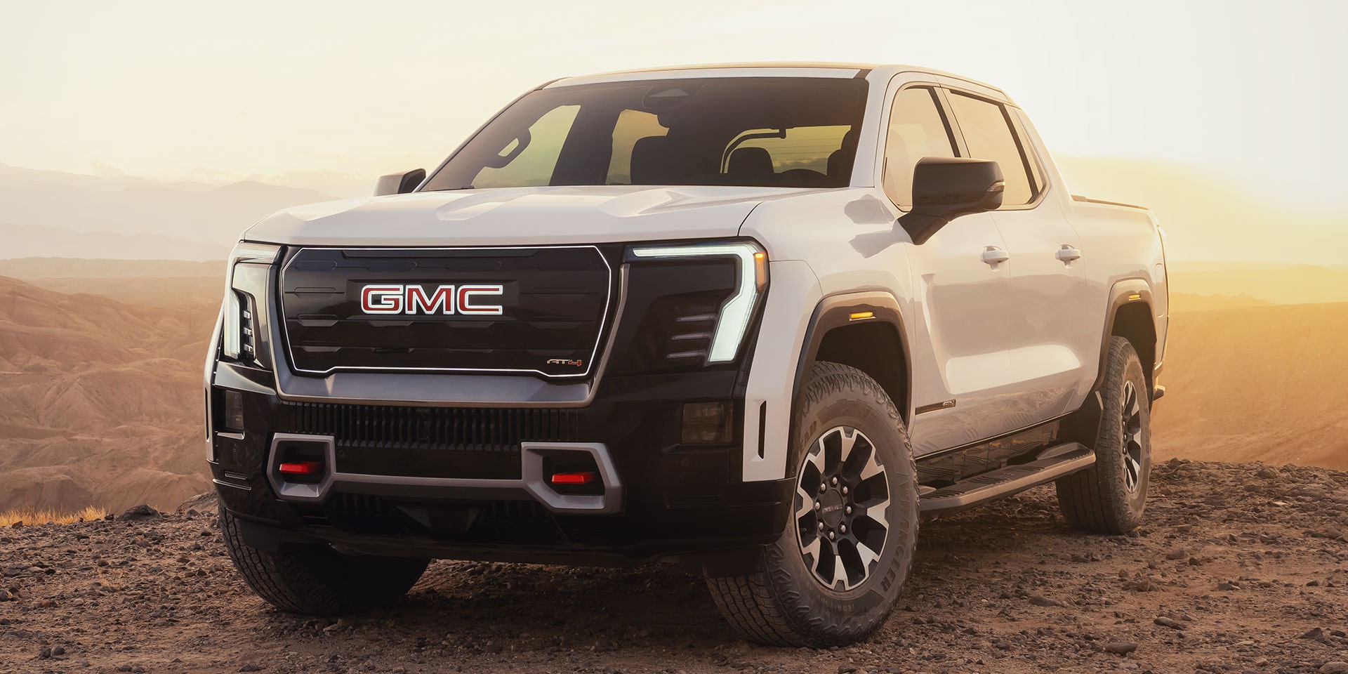A White GMC Sierra EV AT4 Showing Bold Exterior Styling Parked in a Desert Setting