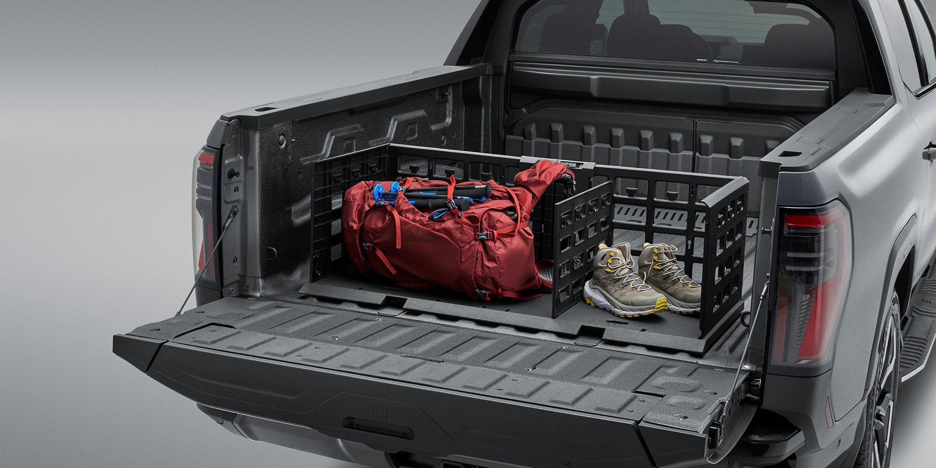 A GMC Sierra EV Truck Bed Featuring Modular Storage Dividers Carrying a Red Duffel Bag