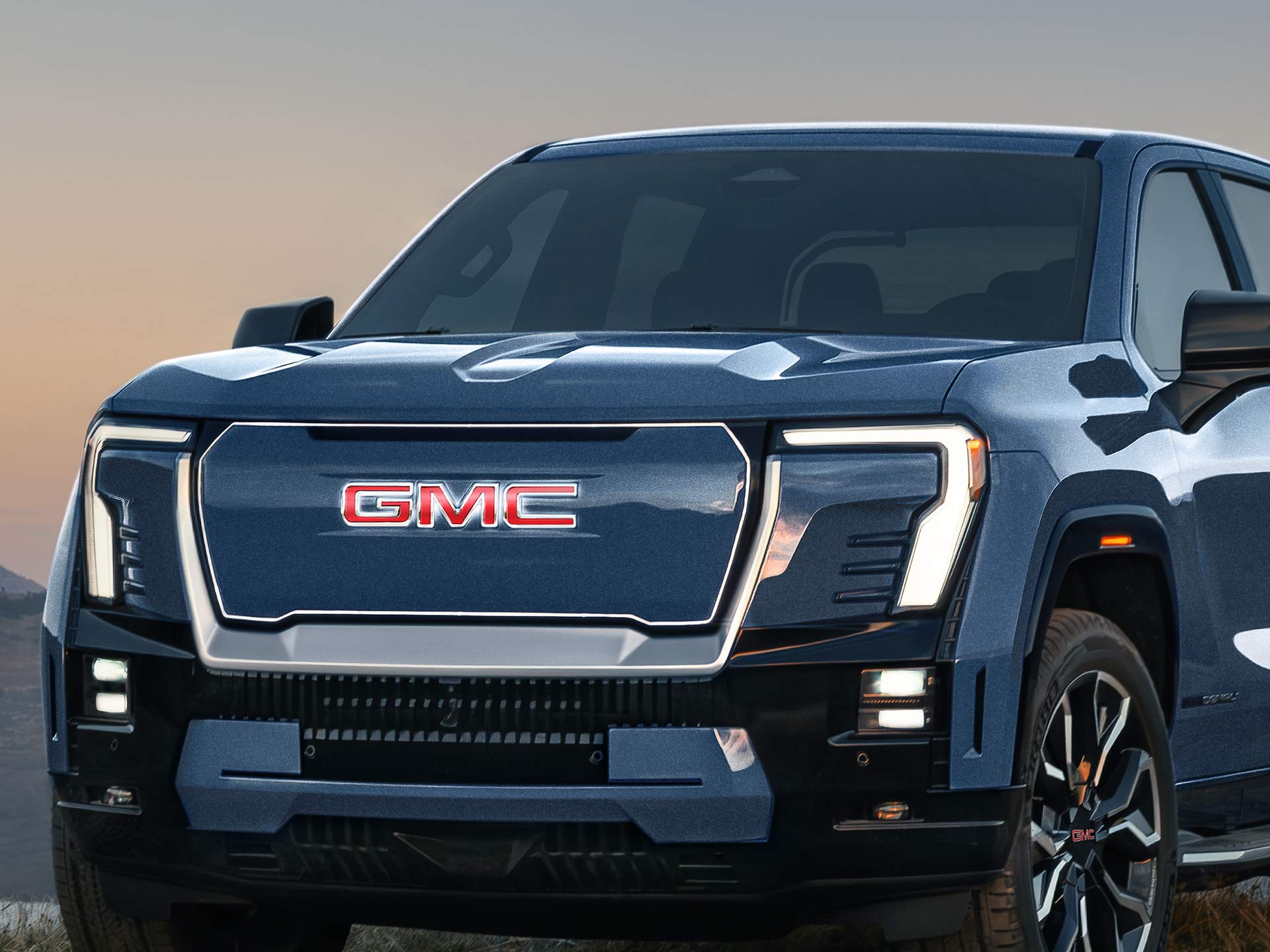 A Close Front View of a GMC Sierra EV Denali with an Illuminated Badge