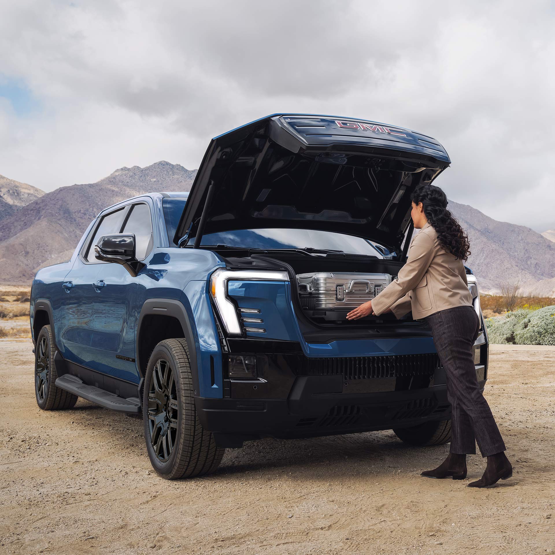 A Woman Loads Luggage into the Spacious eTrunk of the Capable GMC Sierra EV