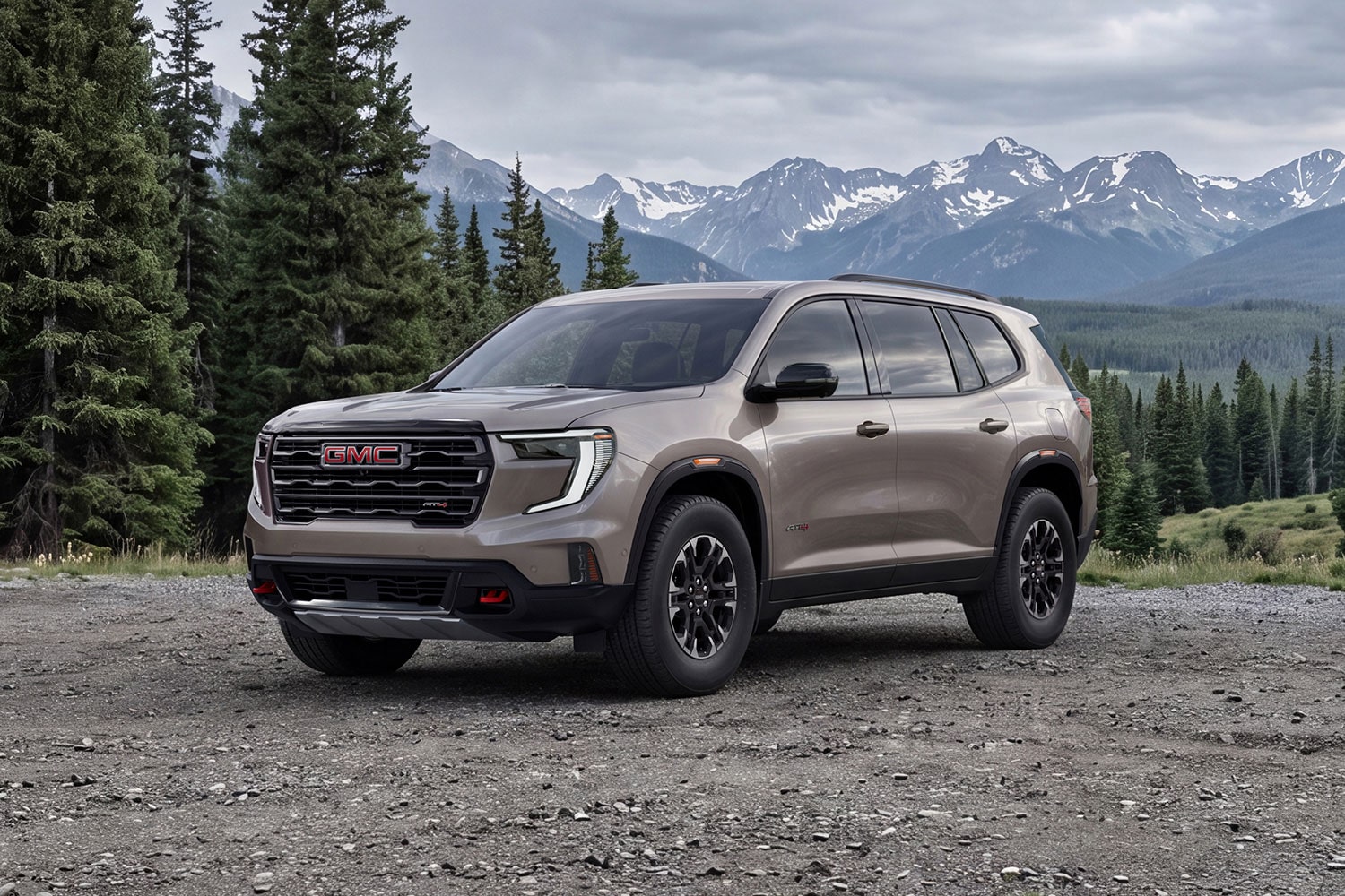A GMC Terrain SUV Parked on a Dirt Road in Front of Pine Trees and Snowy Mountains