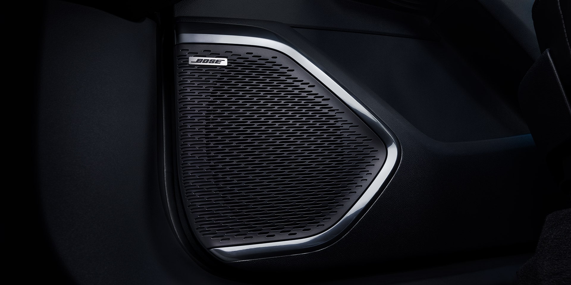 A Close-up of a Bose Speaker Grille with a Silver Trim Inside a Car Door