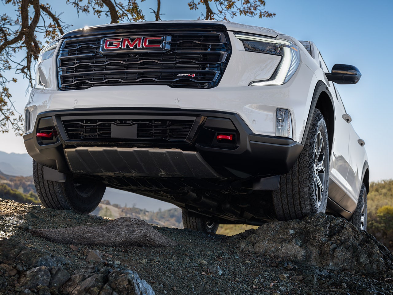 Front View of a White GMC SUV With the GMC Logo on the Grille Parked on Uneven Rocks