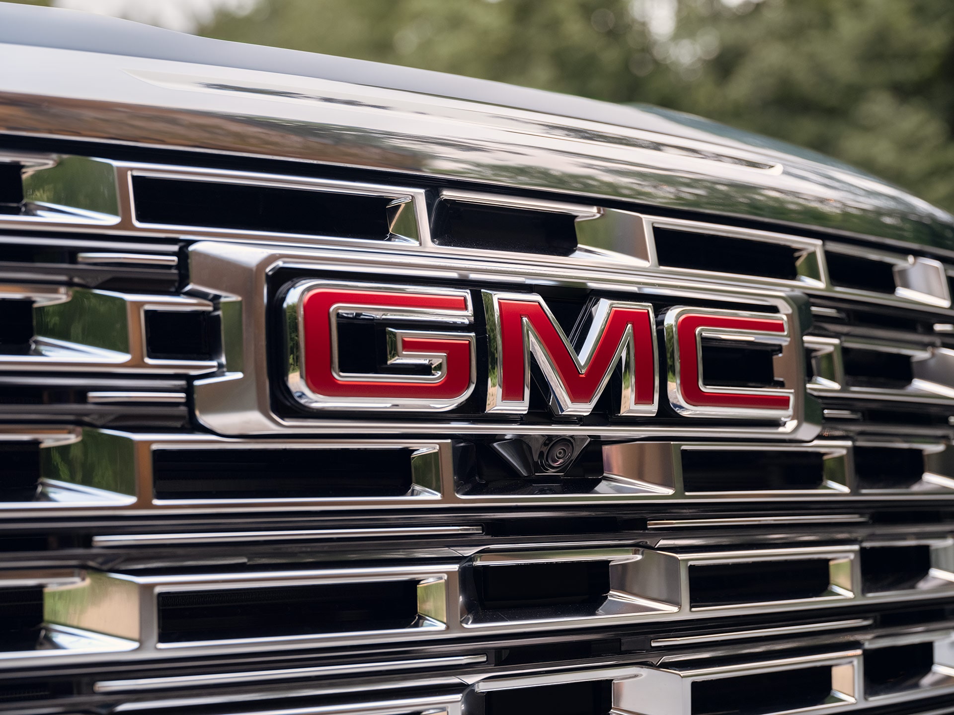A Close-up of a GMC Vehicle's Front Grille with a Red GMC Logo in the Center