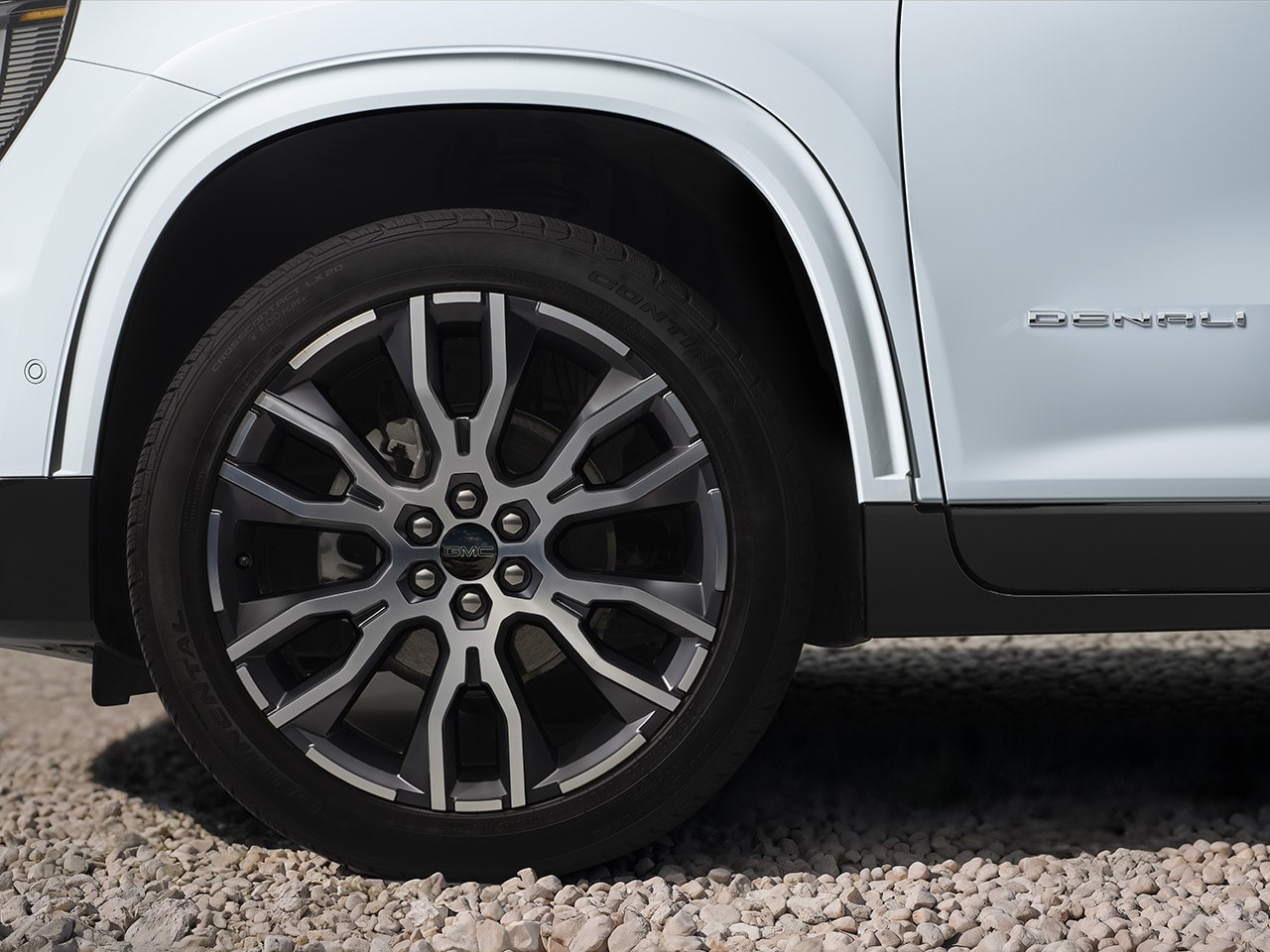 Close-up of a Multi-Spoke Wheel And Tire on a White GMC Denali Vehicle on Gravel