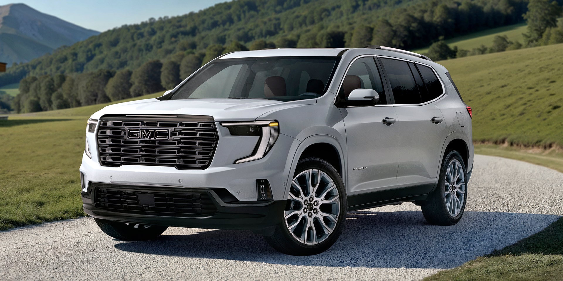 White GMC SUV Parked on a Gravel Path With Lush Green Rolling Hills in the Background Under a Clear Sky