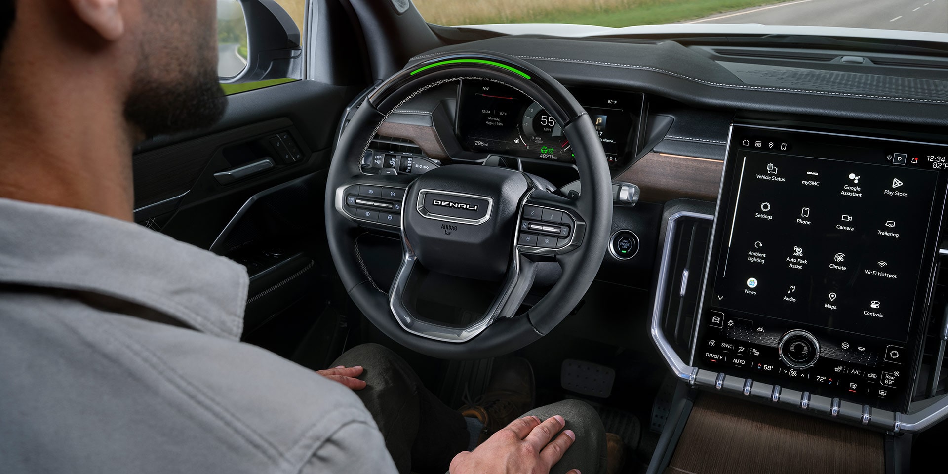 A Man Sitting in the Driver Seat of a GMC Vehicle with his Hands on his Lap, Utilizing the Super Cruise Feature.