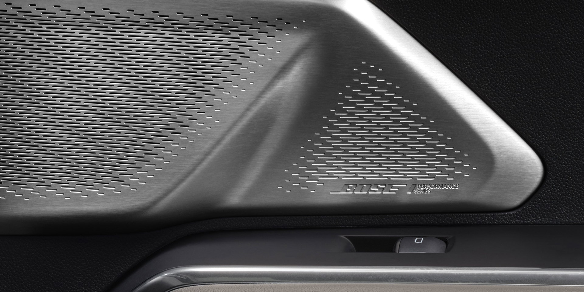 The Interior Door Panel of a GMC Vehicle with a Bose Speaker Grille and Brown Leather with White Stitching