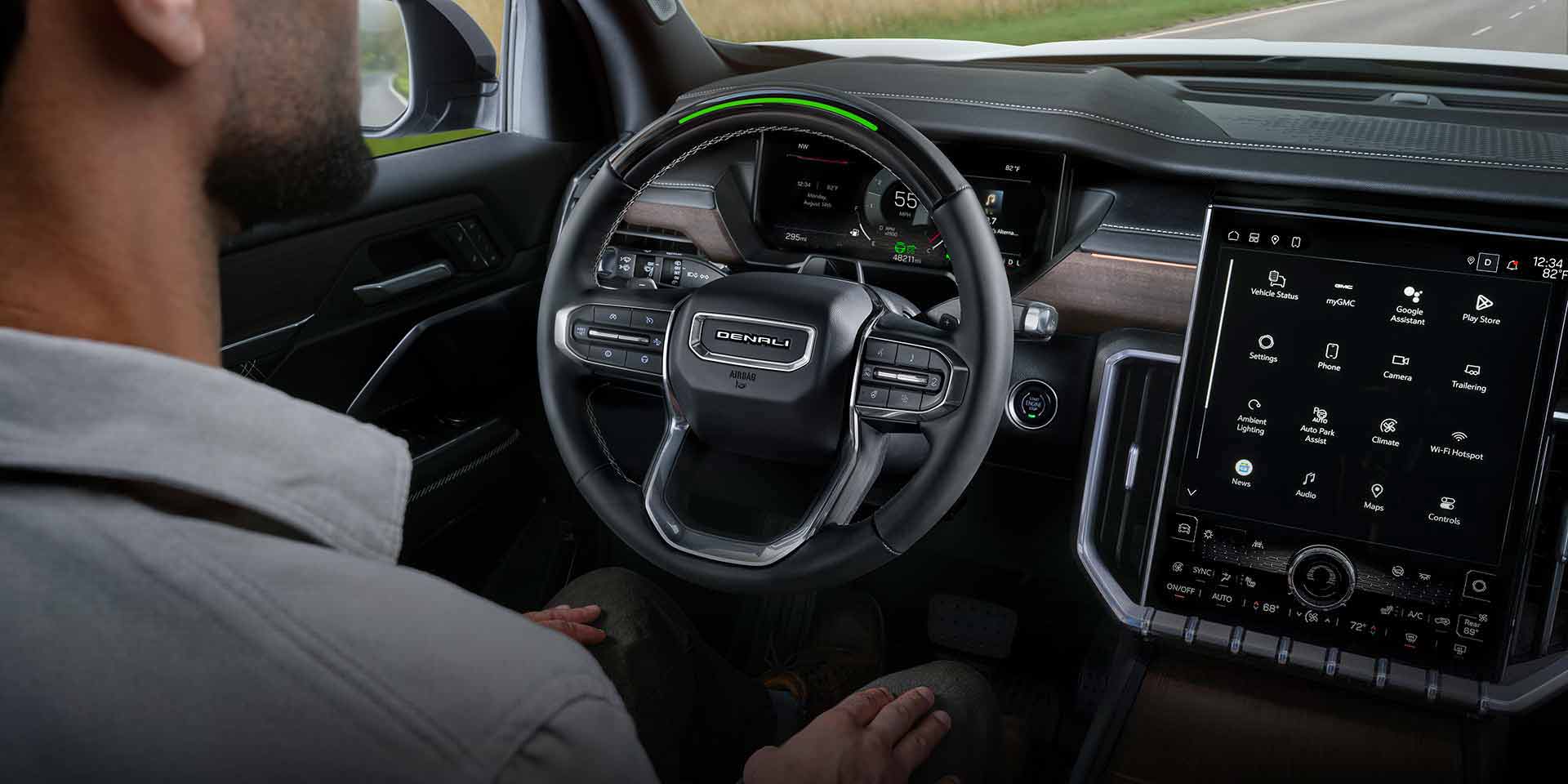 A Man Sitting in the Driver Seat of a GMC Vehicle with his Hands on his Lap, Utilizing the Super Cruise Feature.