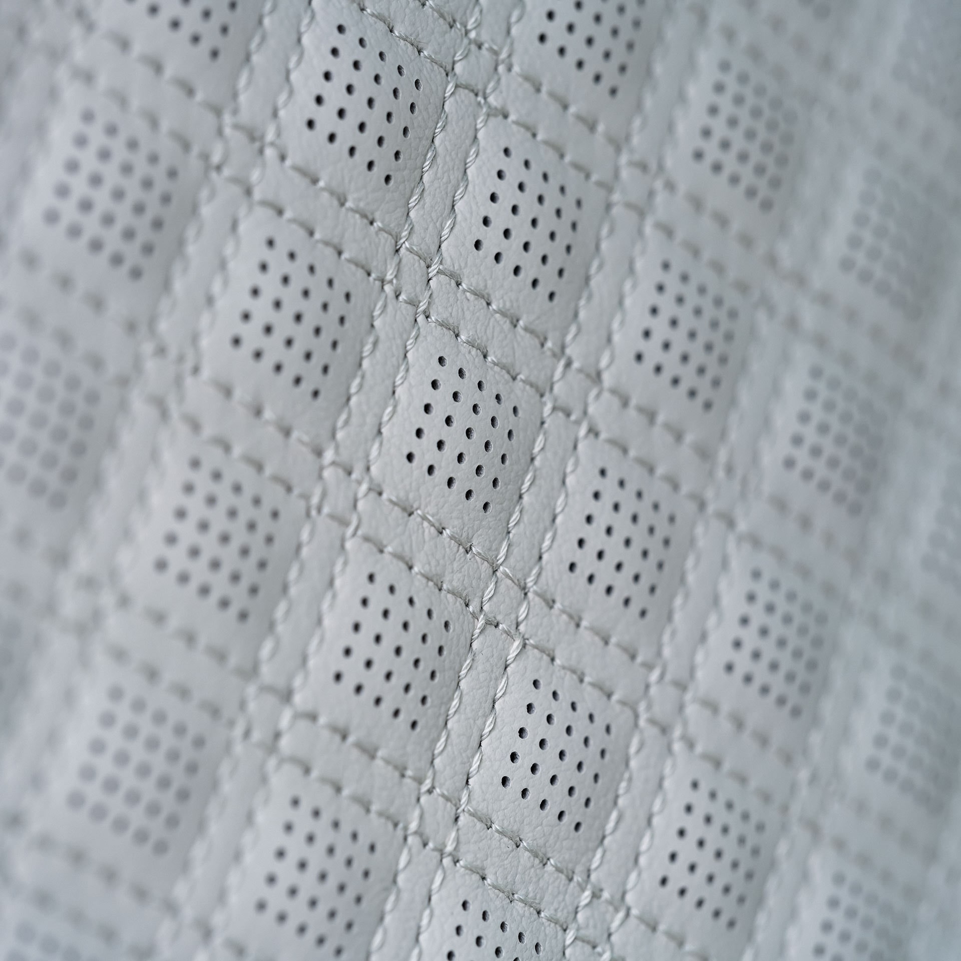 A Close-up View of Light Gray Quilted Perforated Leather Seating with Diamond Stitching
