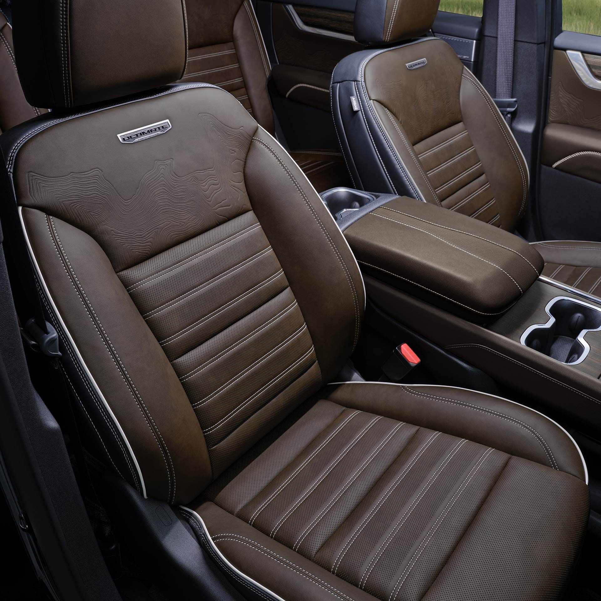 The Interior of a GMC Denali with Brown Leather Seats Featuring White Stitching and the Denali Logo