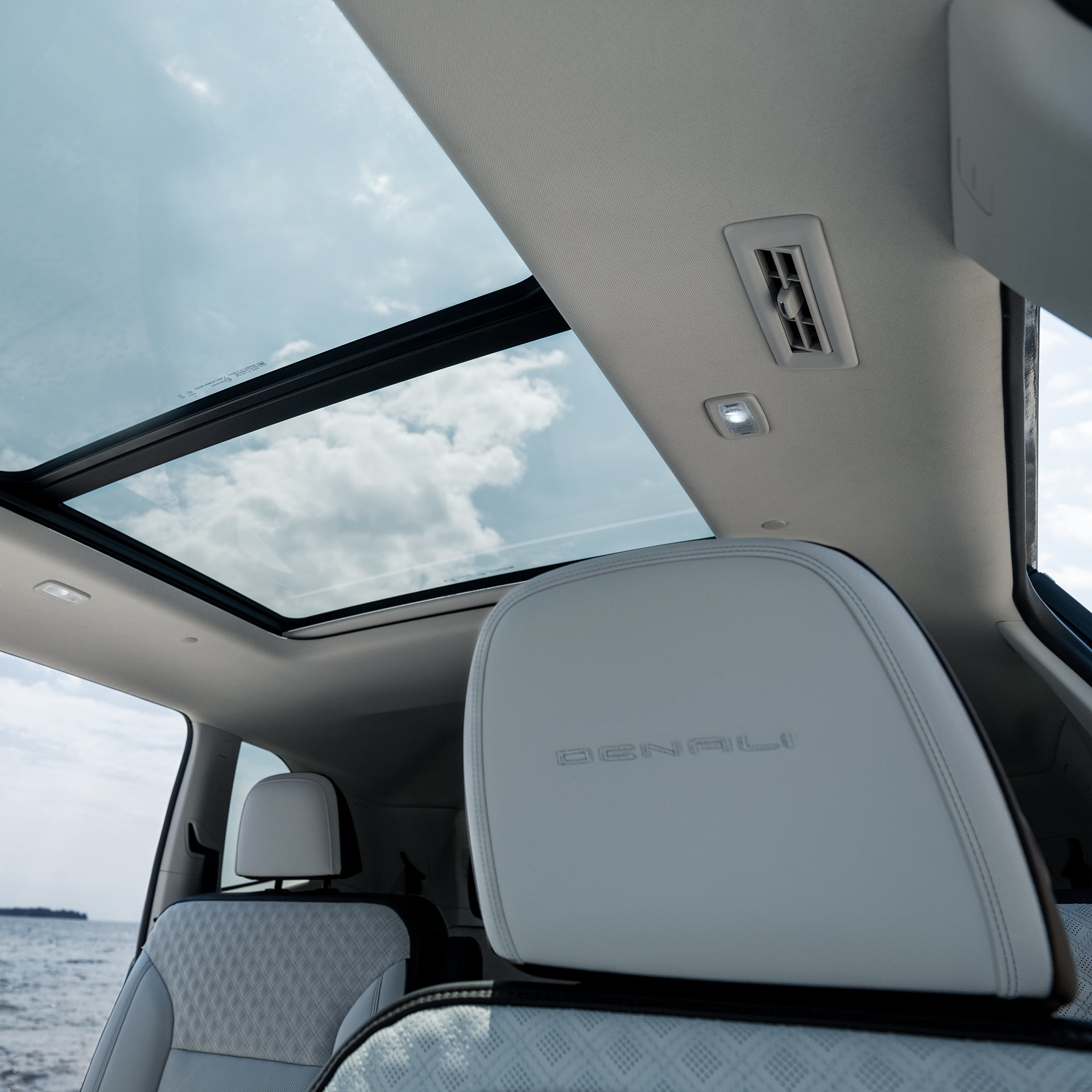 A Panoramic Sunroof in a GMC Vehicle from the Rear Seats with a View of the Ocean