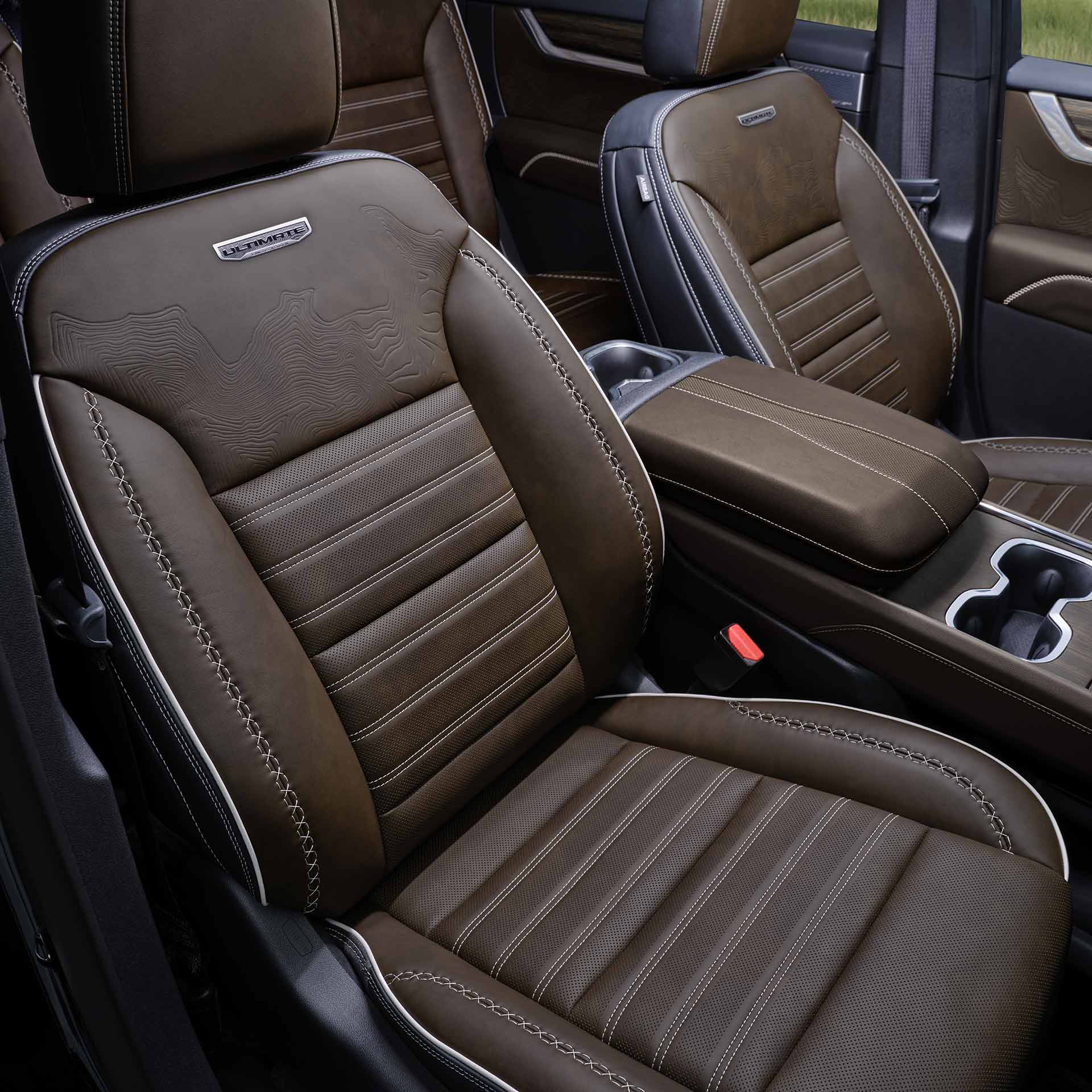 The Interior of a GMC Denali with Brown Leather Seats Featuring White Stitching and the Denali Logo