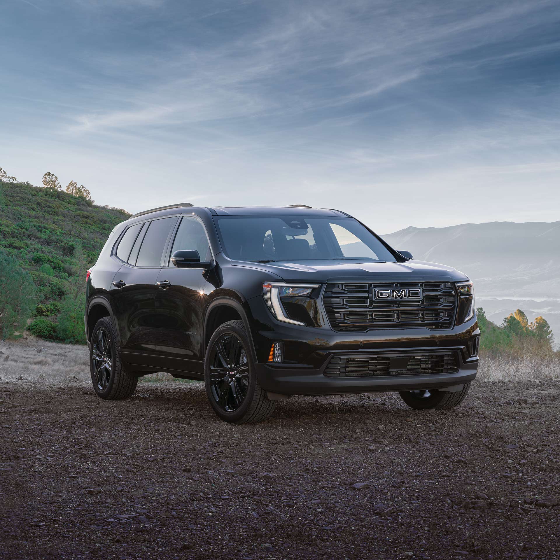A Black GMC SUV Parked on a Dirt Road with a Grille Featuring a Silver GMC Logo