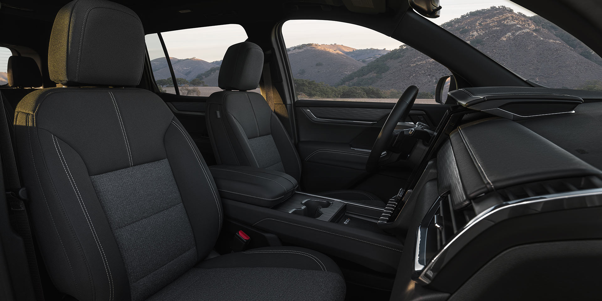 The Interior Front Seats of a GMC Vehicle with Dark Gray Fabric and White Stitching