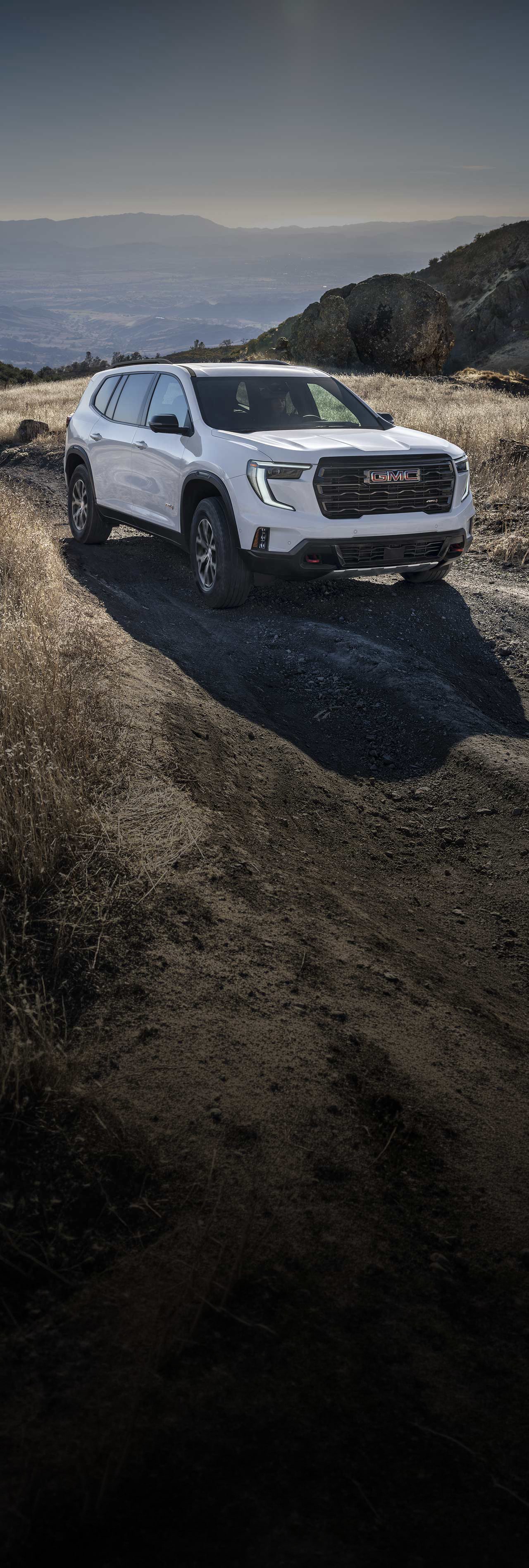 White GMC SUV on a Dirt Road In a Mountainous Landscape