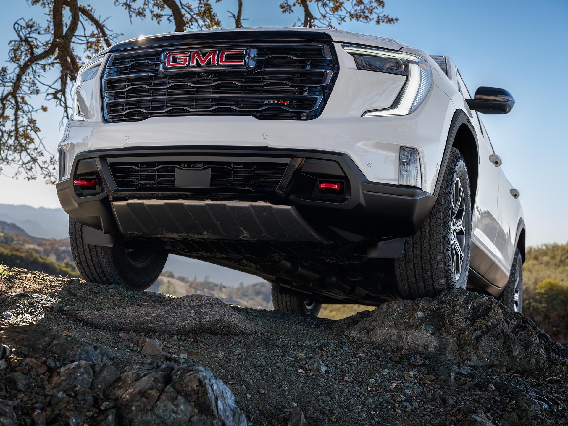 Front View of a White GMC SUV With the GMC Logo on the Grille Parked on Uneven Rocks