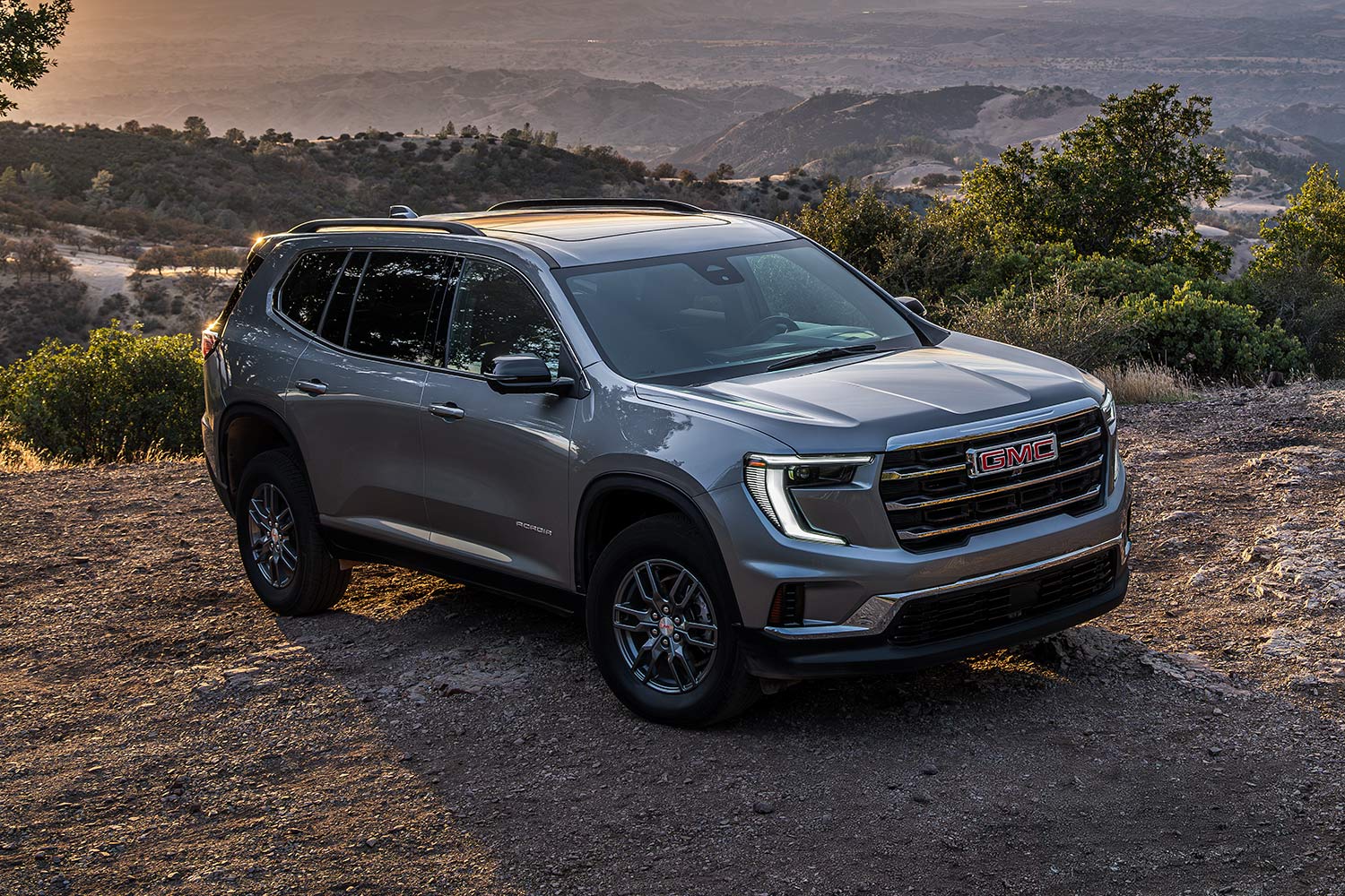 Gray GMC SUV Parked on a Dirt Path Overlooking a Scenic Valley With Mountains in the Distance