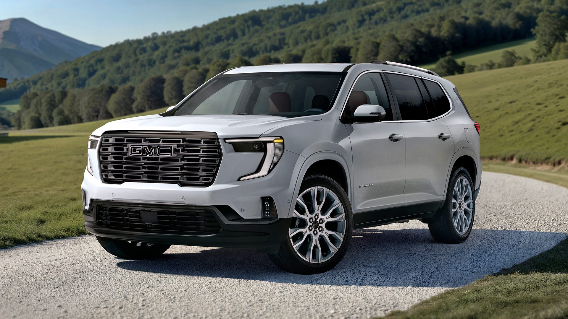 White GMC SUV Parked on a Gravel Path With Lush Green Rolling Hills in the Background Under a Clear Sky