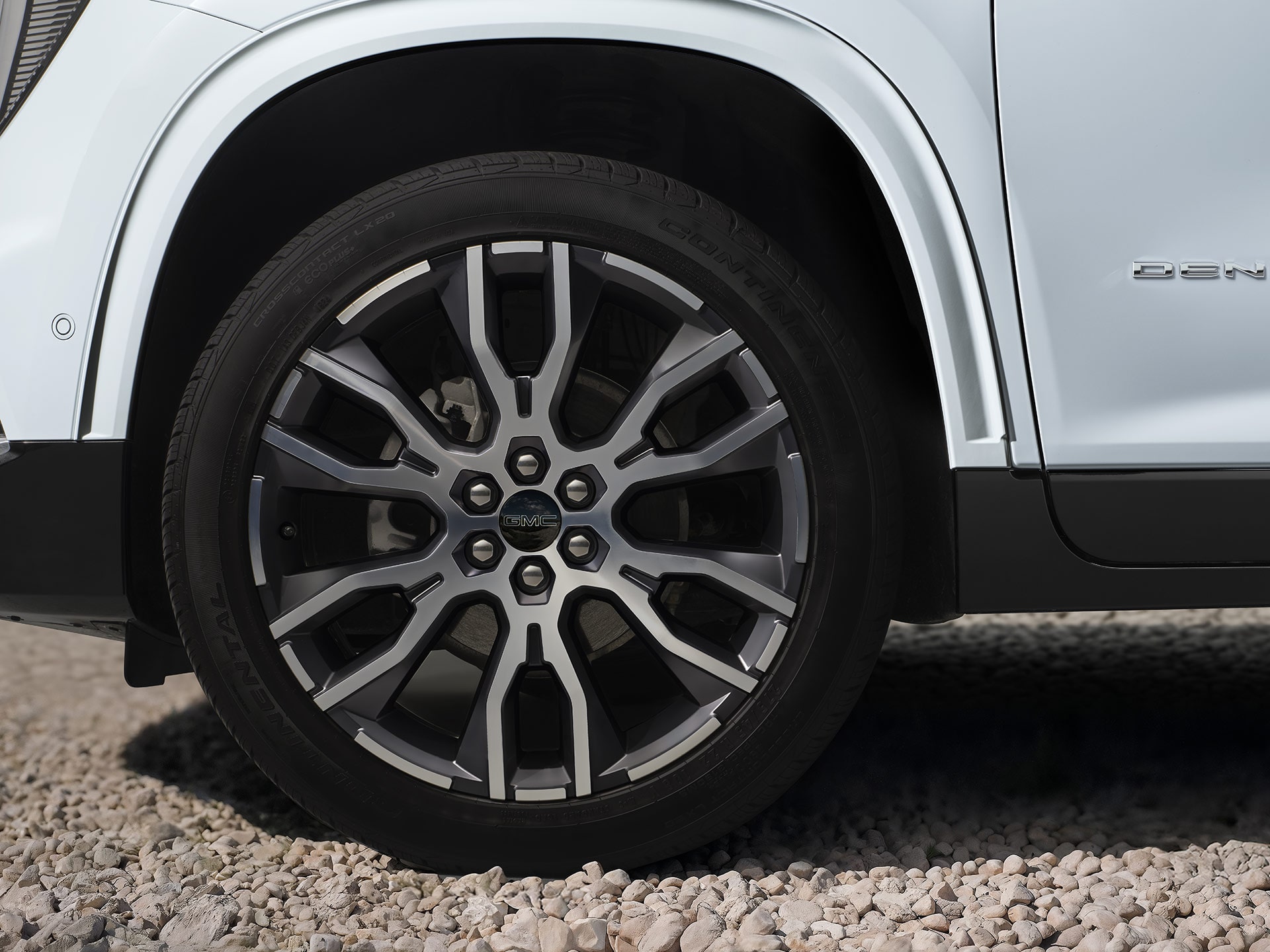 Close-up of a Multi-Spoke Wheel And Tire on a White GMC Denali Vehicle on Gravel