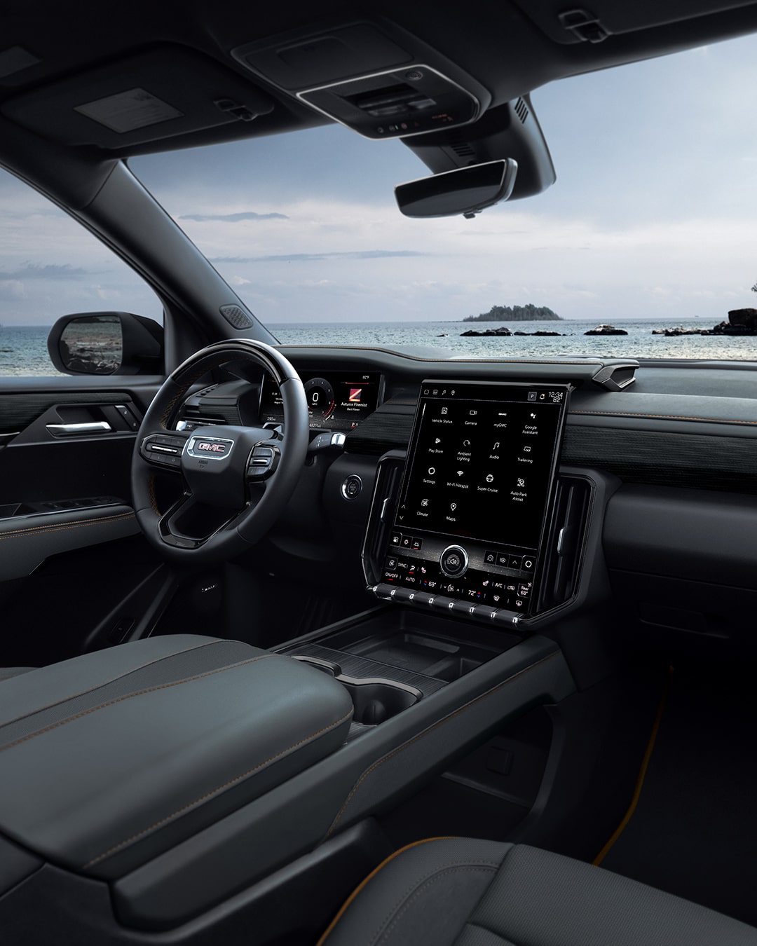 Passenger Side View of the Driver Seat and Dashboard of a GMC Vehicle with a Body of Water and Trees in the Distance.